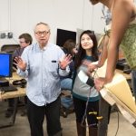 Mel Chin and his Exhibition Coordinator Audrey Liu work with a fully-wired Kelsey Hamilton.