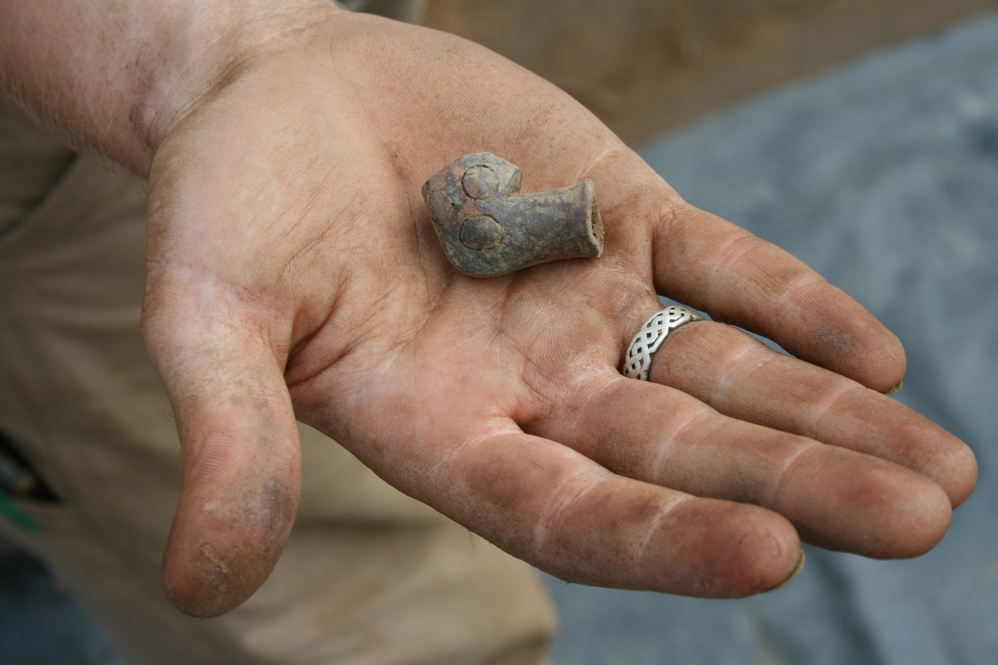 Joara clay pipe hand holds small piece of clay pipe artifact