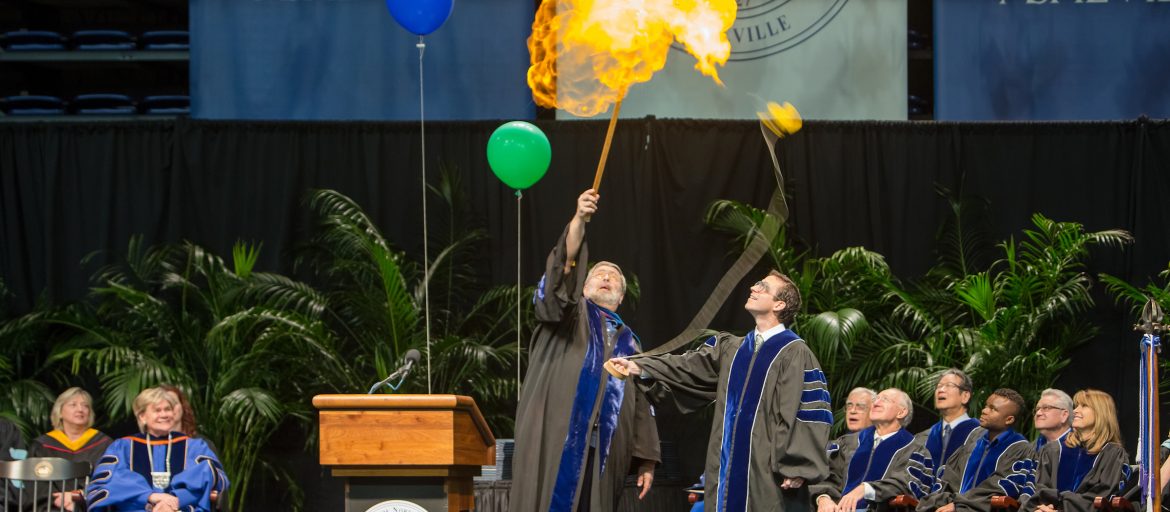 The speaker at commencement lighting a balloon on fire.