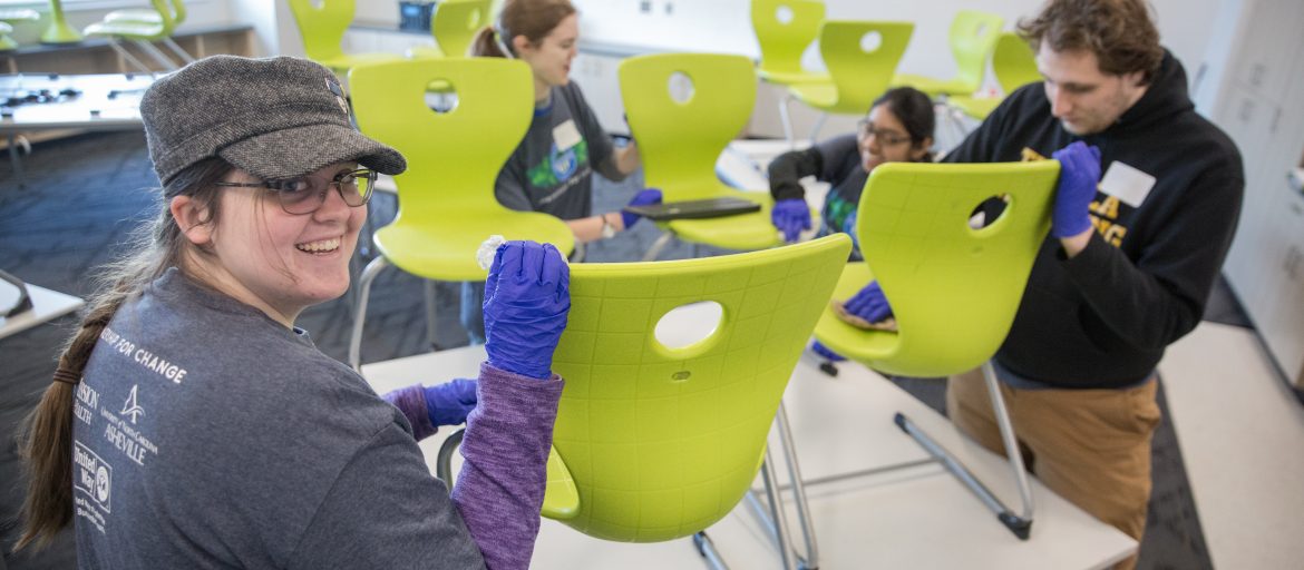 Student volunteers cleaning chairs