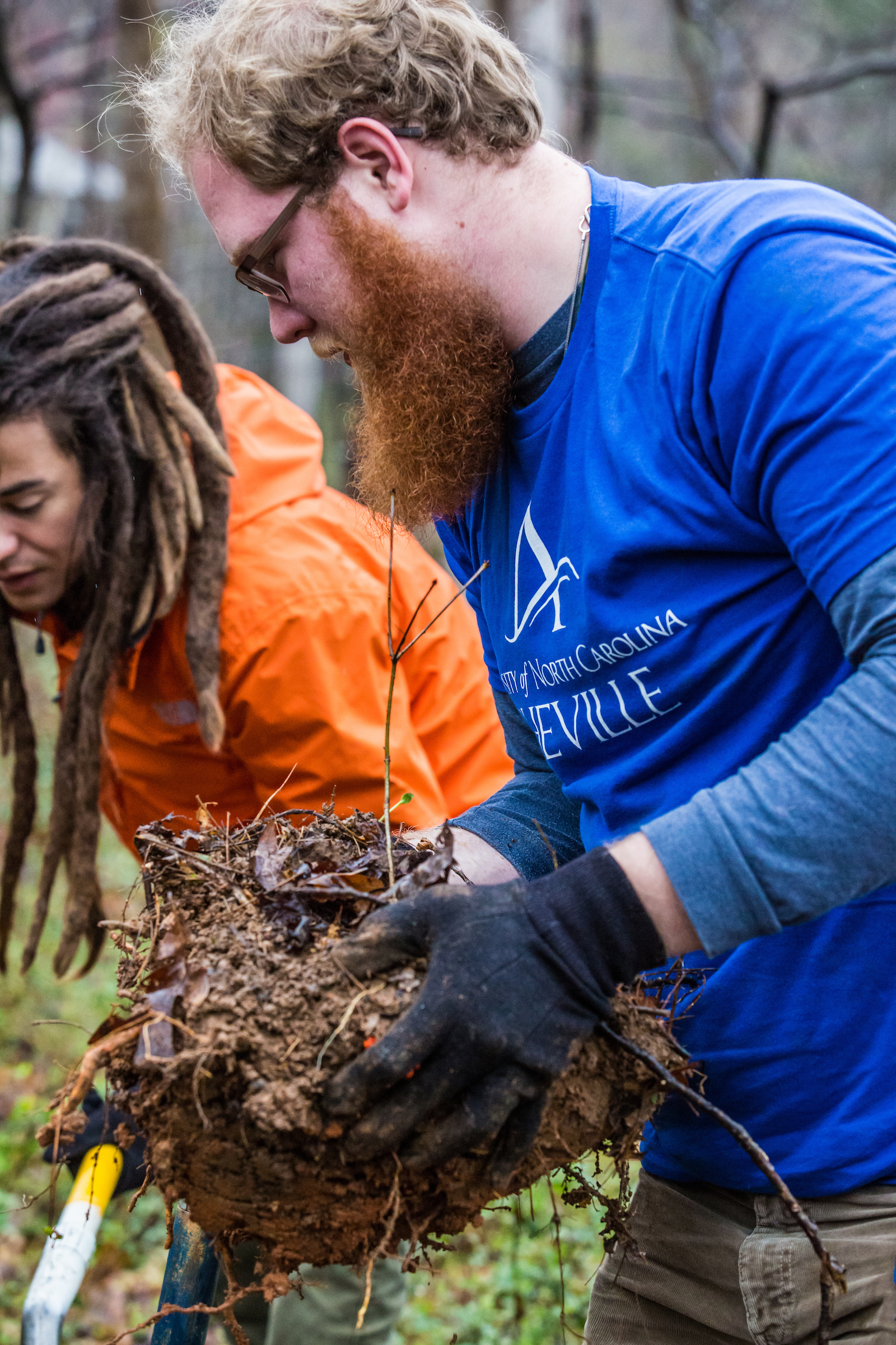 A student holding soil and a tree sapling.