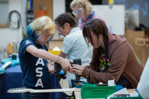 Two young women operating a power drill