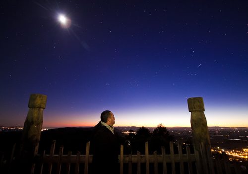 Matmua is sillhouetted against the night sky with stars and indigenous sculptures visible