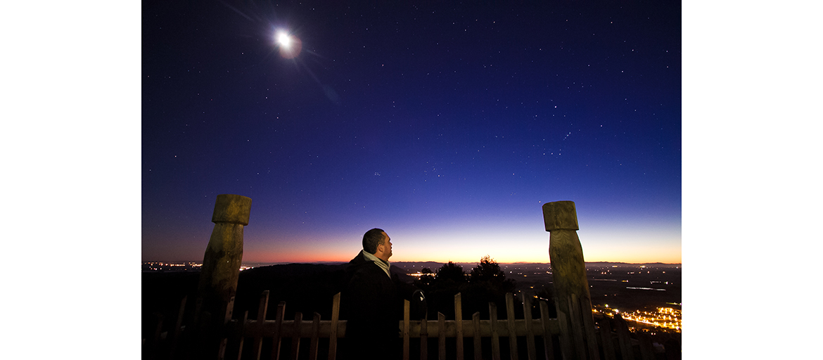Matamua star gazing profile web Matmua is sillhouetted against the night sky with stars and indigenous sculptures visible