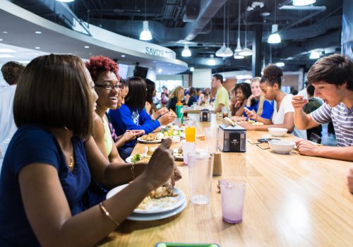 students eat and laugh in a dining hall