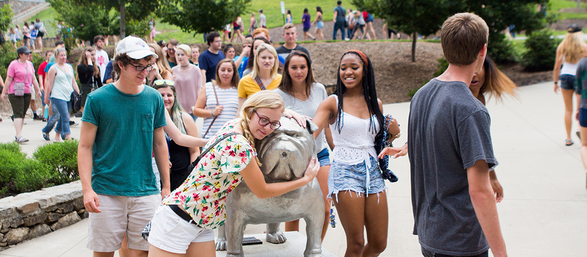 Students hug the statue of Rocky, UNC Asheville's mascot