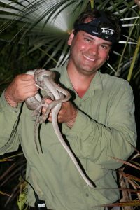 a man holding a snake and smiling