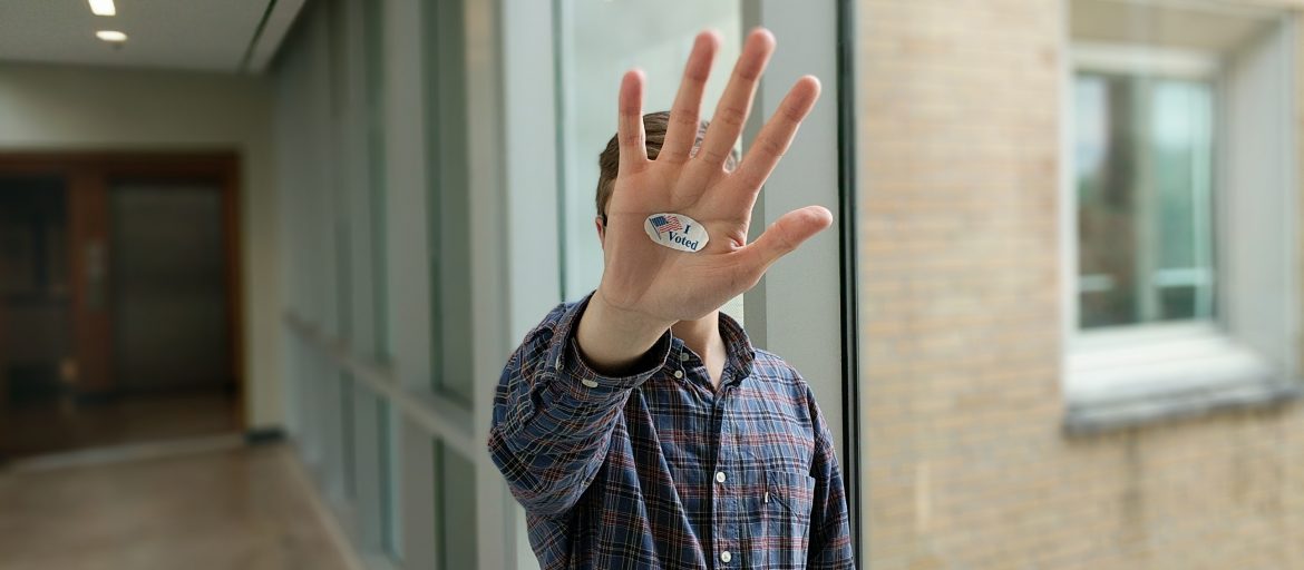 a person holds up their hand with an I Voted sticker on their palm