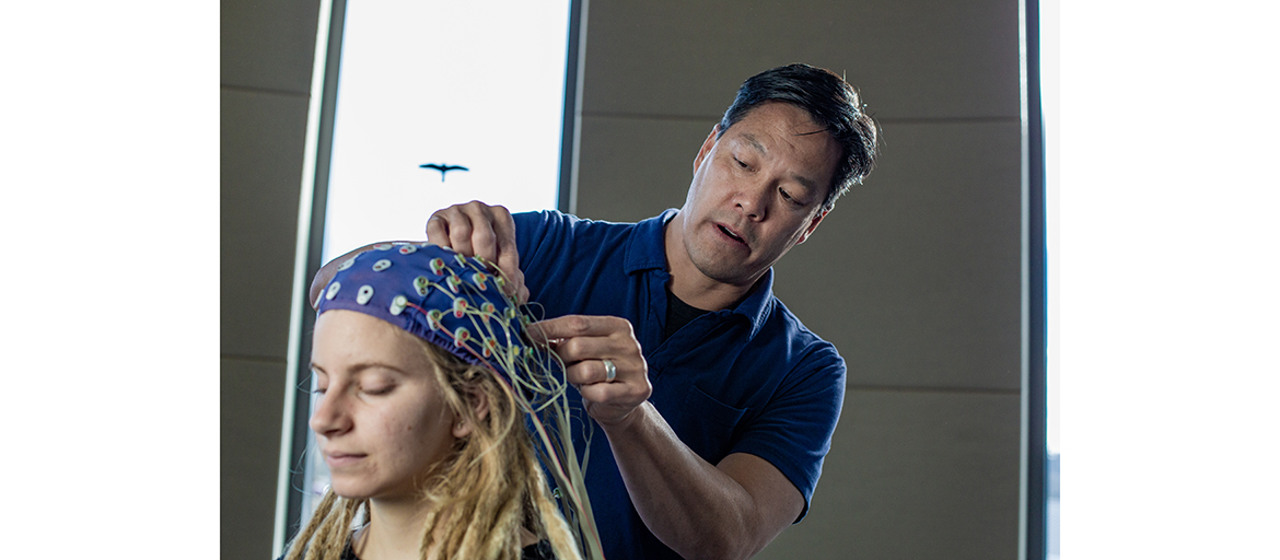 Pat Foo and Julie Neumark – Dec 2019 Patrick Foo attaches wires to a 64-channel electroencephalogram (EEG) cap that monitors brain activity