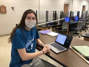 young woman with a mask in front of a laptop
