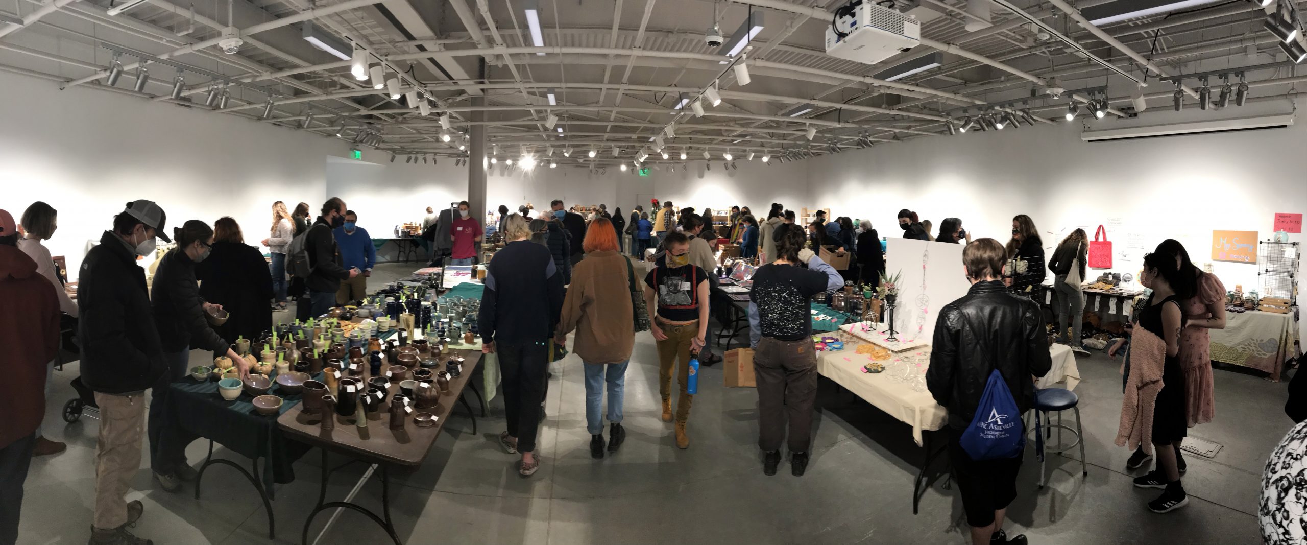 ArtSale_Fall21 a crowded room with tables displaying ceramic art