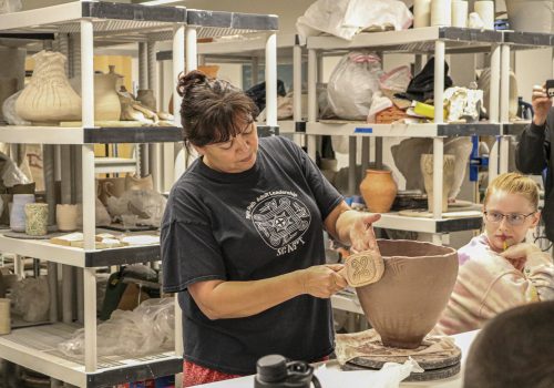 Tara McCoy, Cherokee ceramicist and NEA endowed artist, demonstrates shaping pottery using Cherokee tools and techniques with a class of UNC Asheville students.
