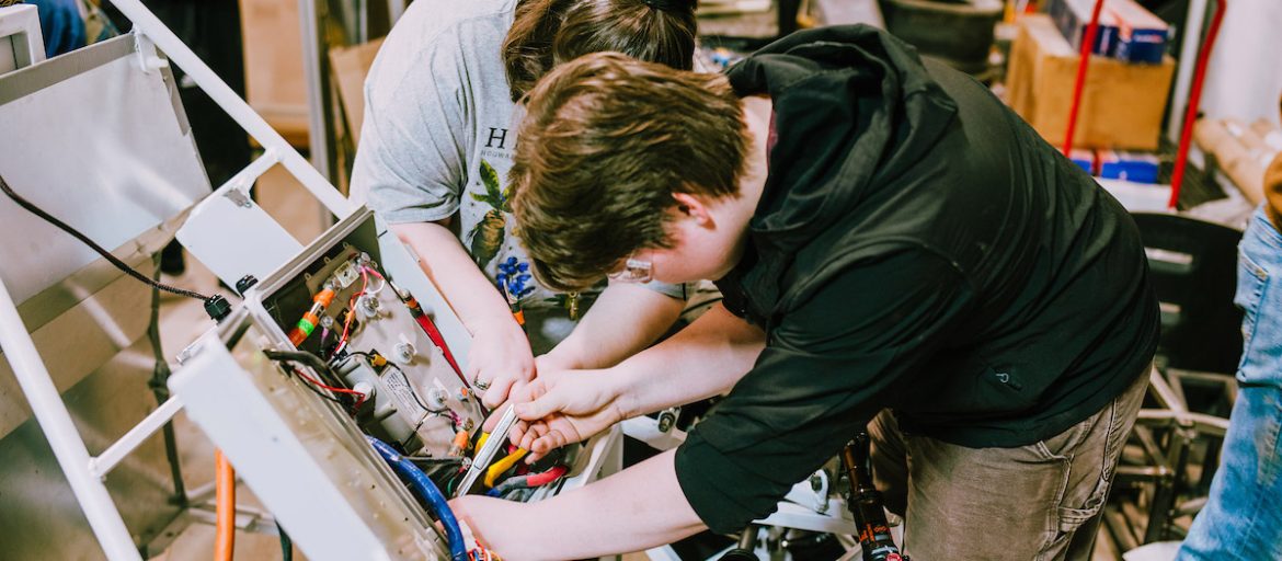 a photo of students working on a car in STEAM studios.