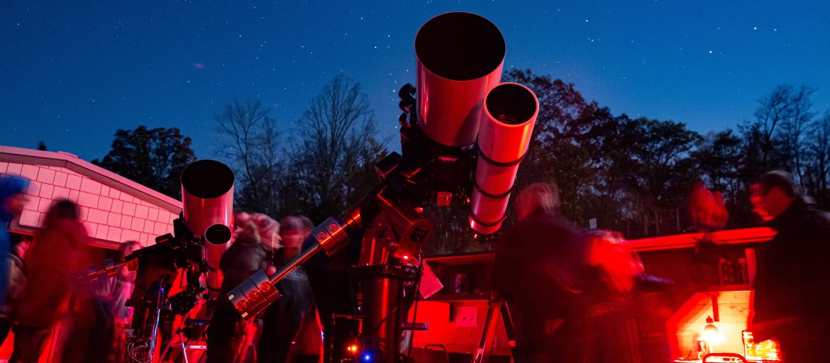 lookout observatory at night, with multiple people gathered around a large telescope