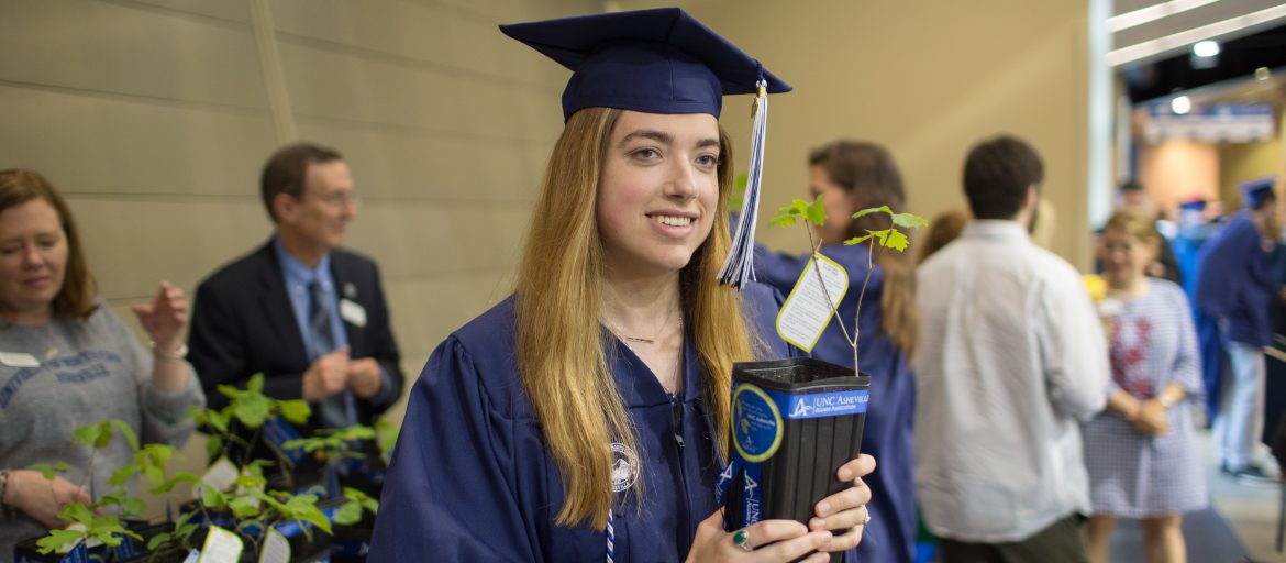 Graduate holding a sapling