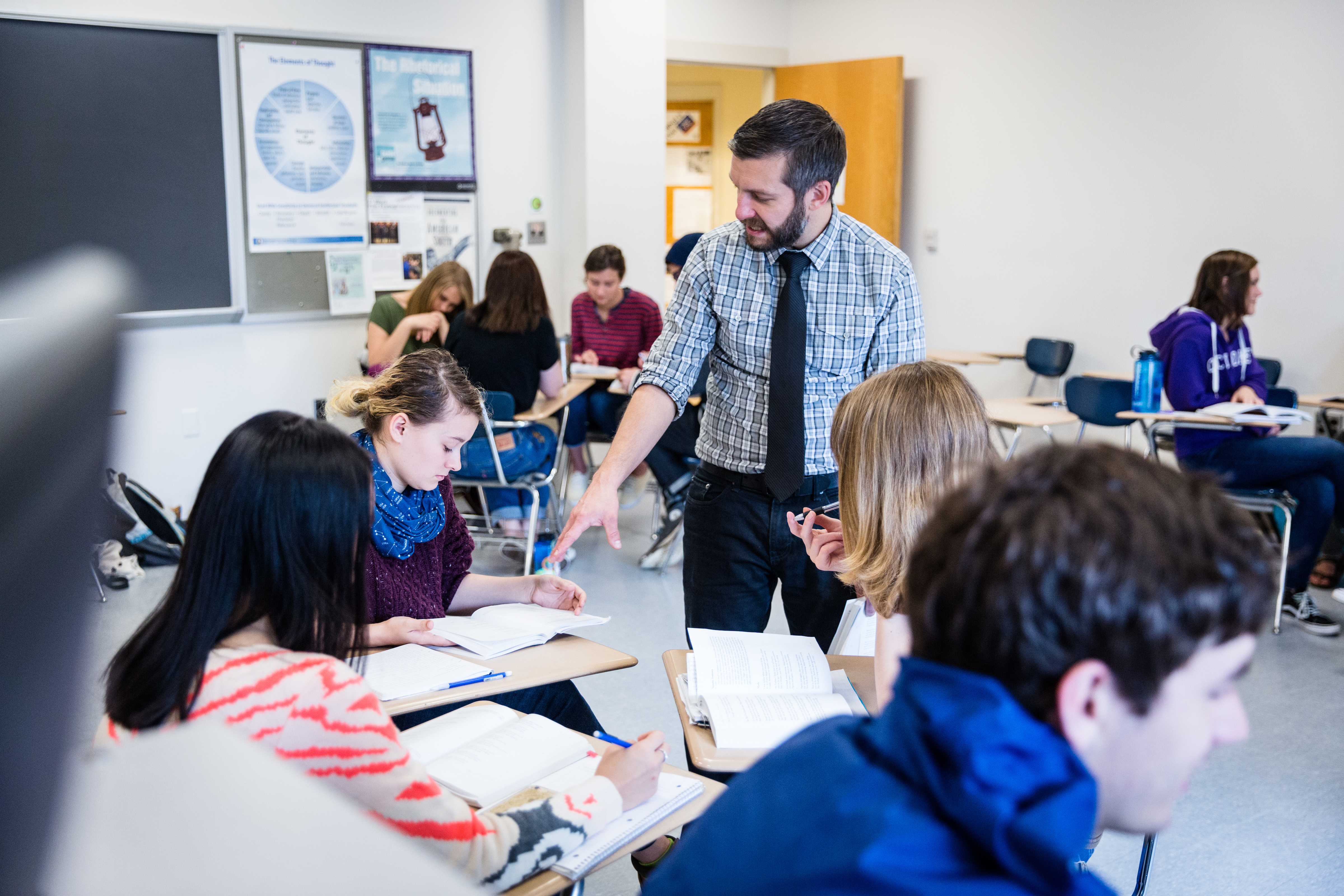 A professor in a classroom explaining something to a group of students.
