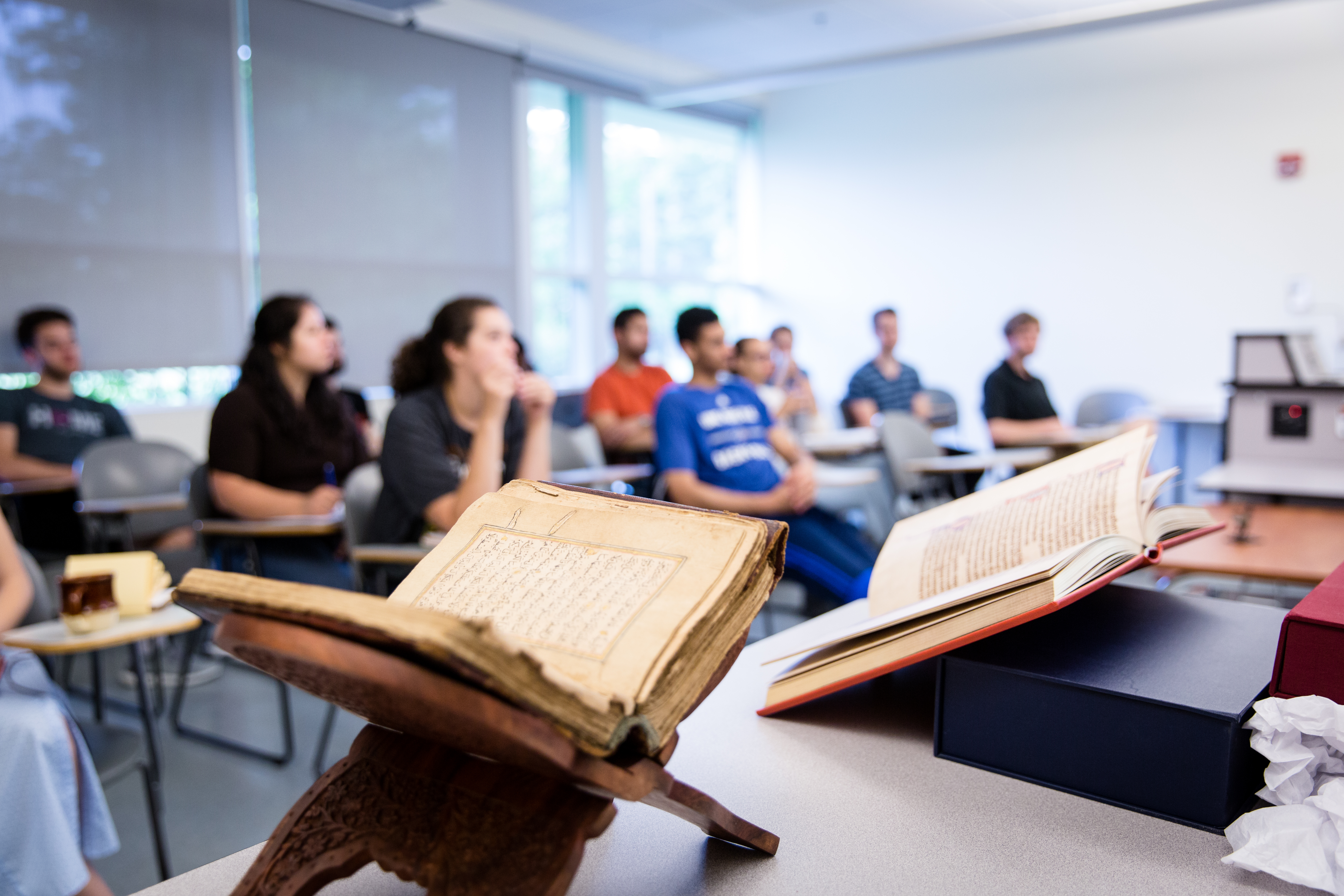 A close-up of two books in front of a classroom full of students.