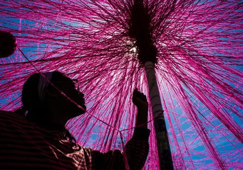 A student tying yarn around a pole for an art project.