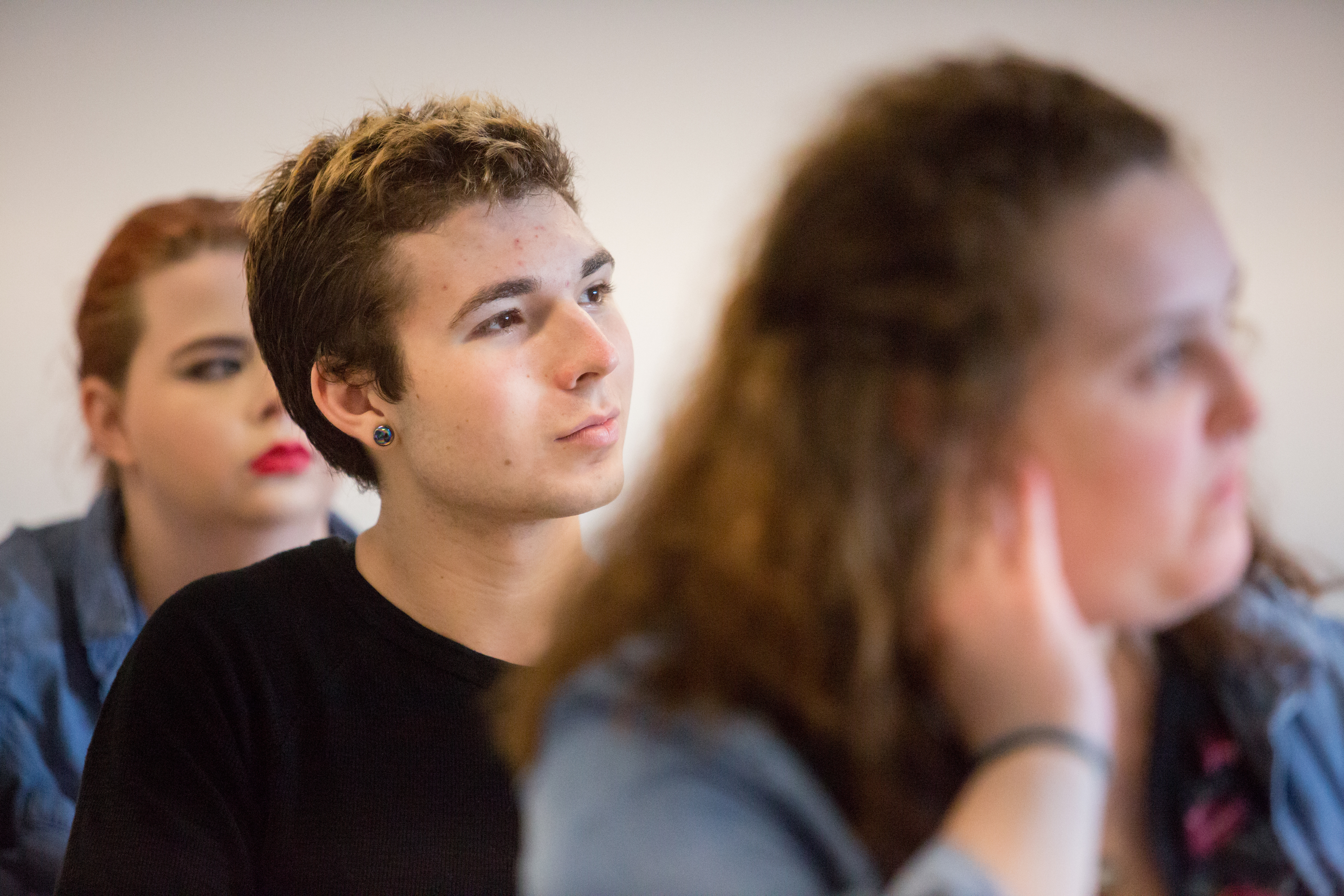 Close-up of three students listening to a lecture.