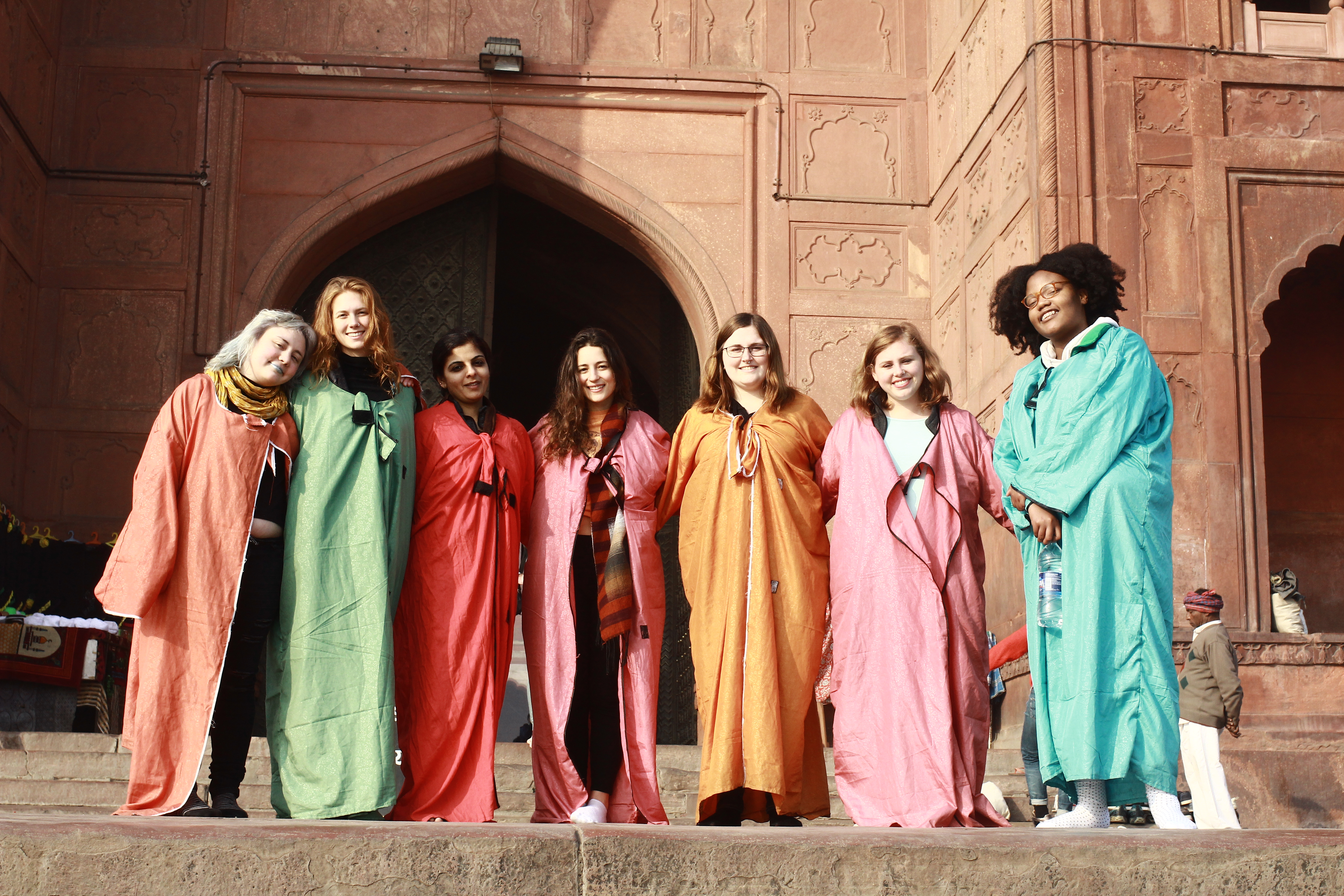A group of students in traditional clothing standing in front of a building with Moroccan architechture.
