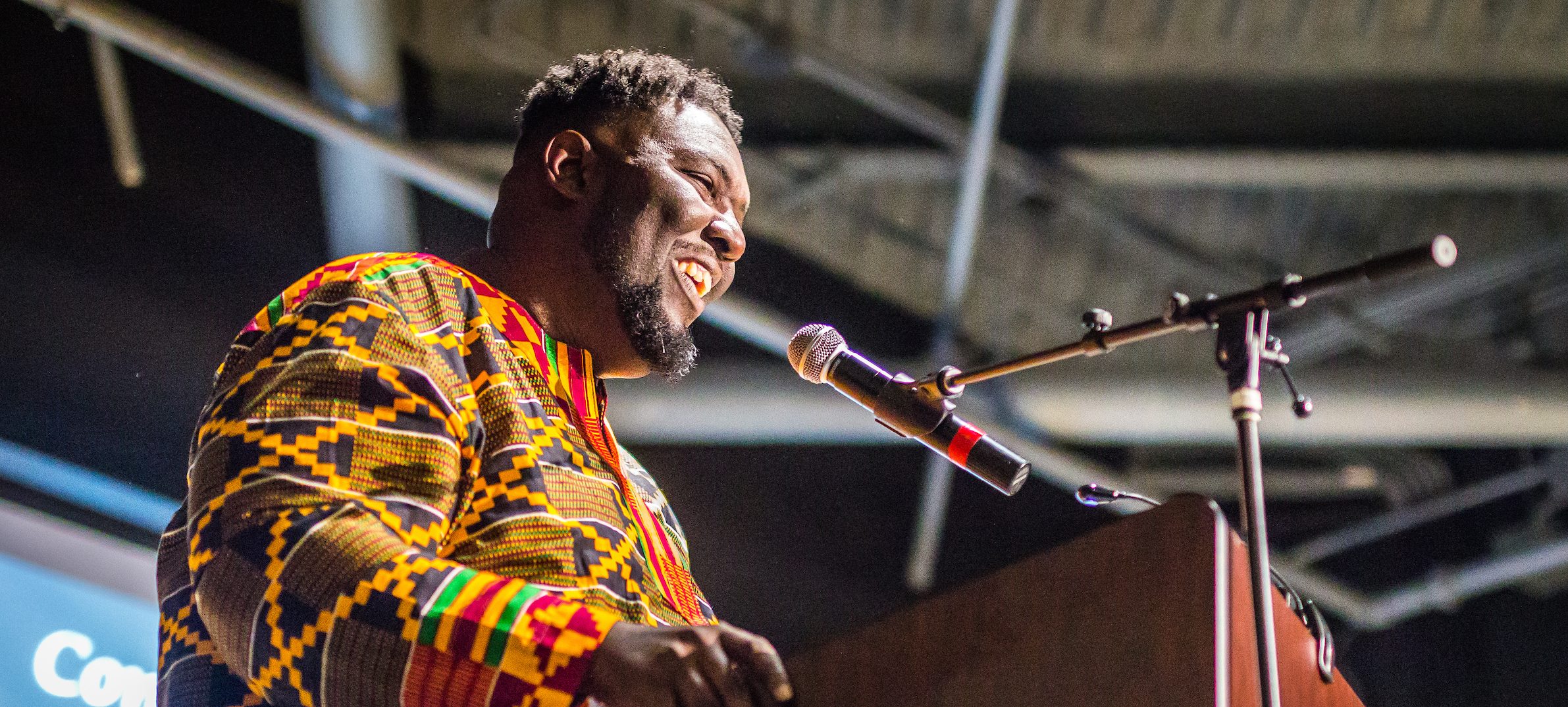 A close-up of a speaker at a podium in traditional African clothing.