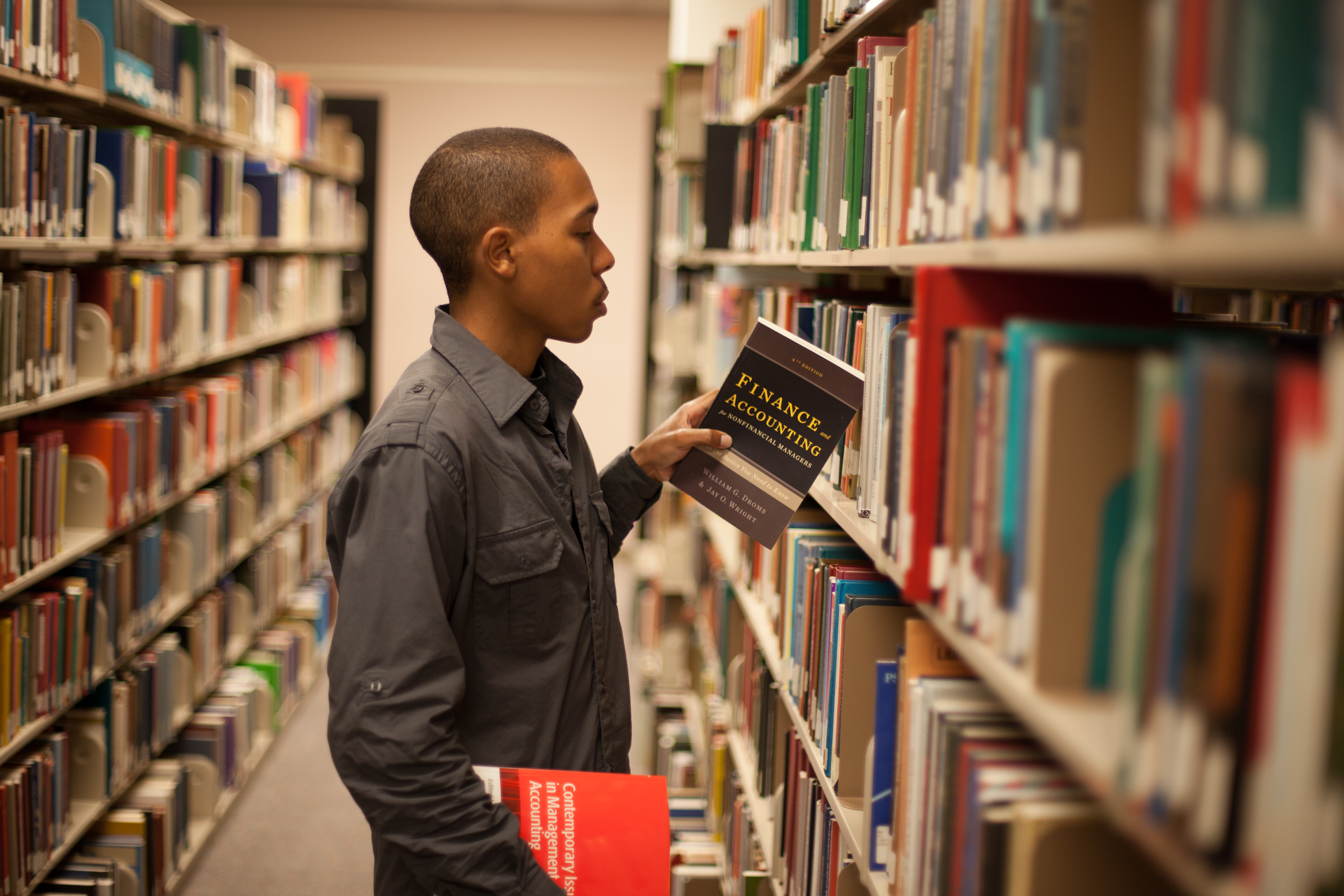 Student in UNC Asheville's Ramsey Library getting a book off the shelf
