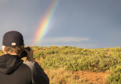 A student taking a picture of a rainbow.