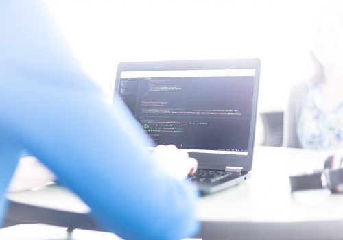 Close-up of a student writing code on a laptop.