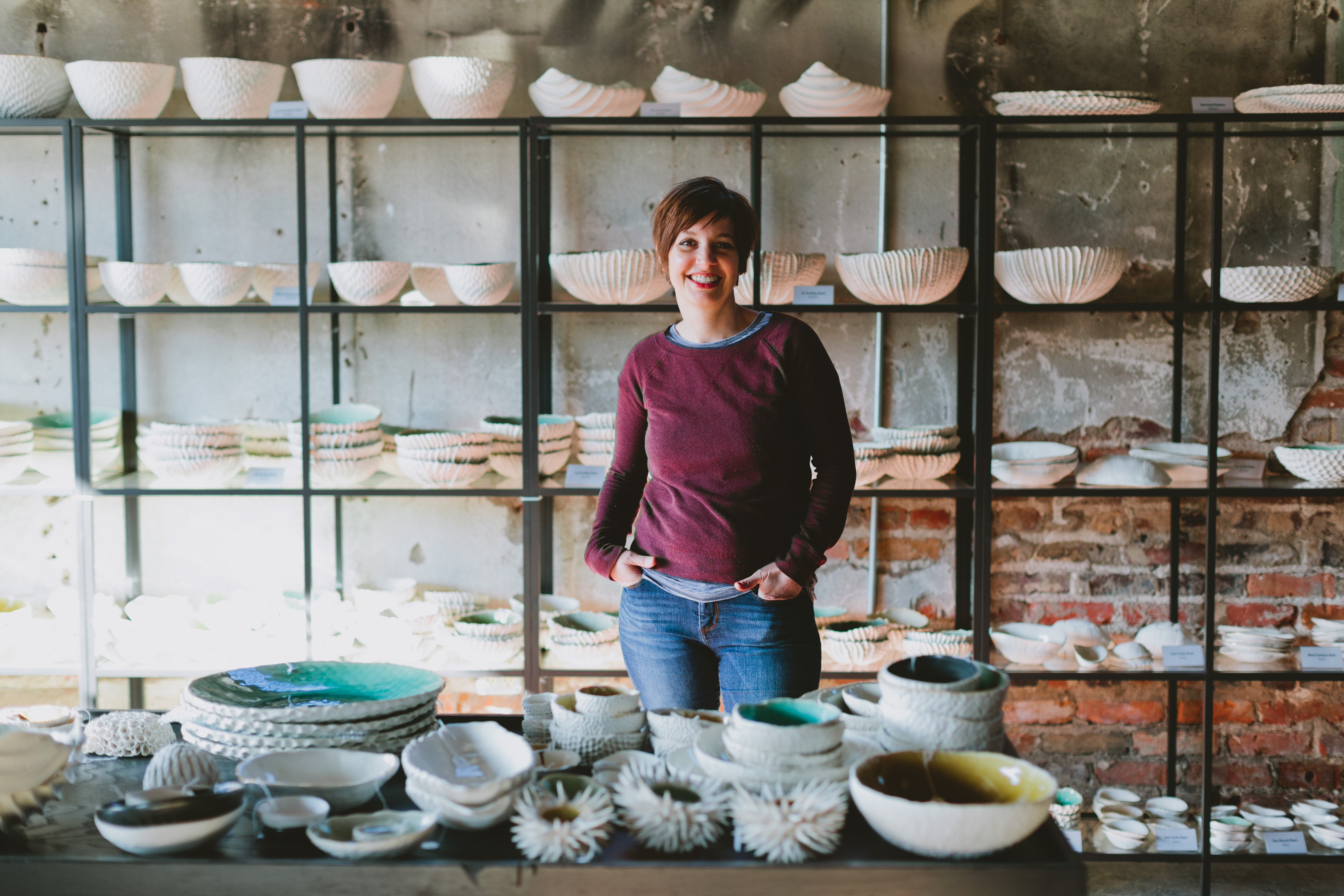 A student standing behind a table with ceramic plates and bowls.