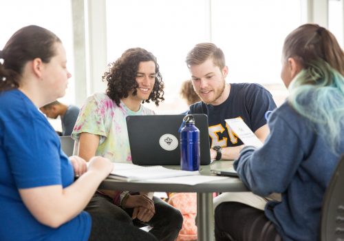 Students sitting at table in atrium in Rhoades-Robinson Hall