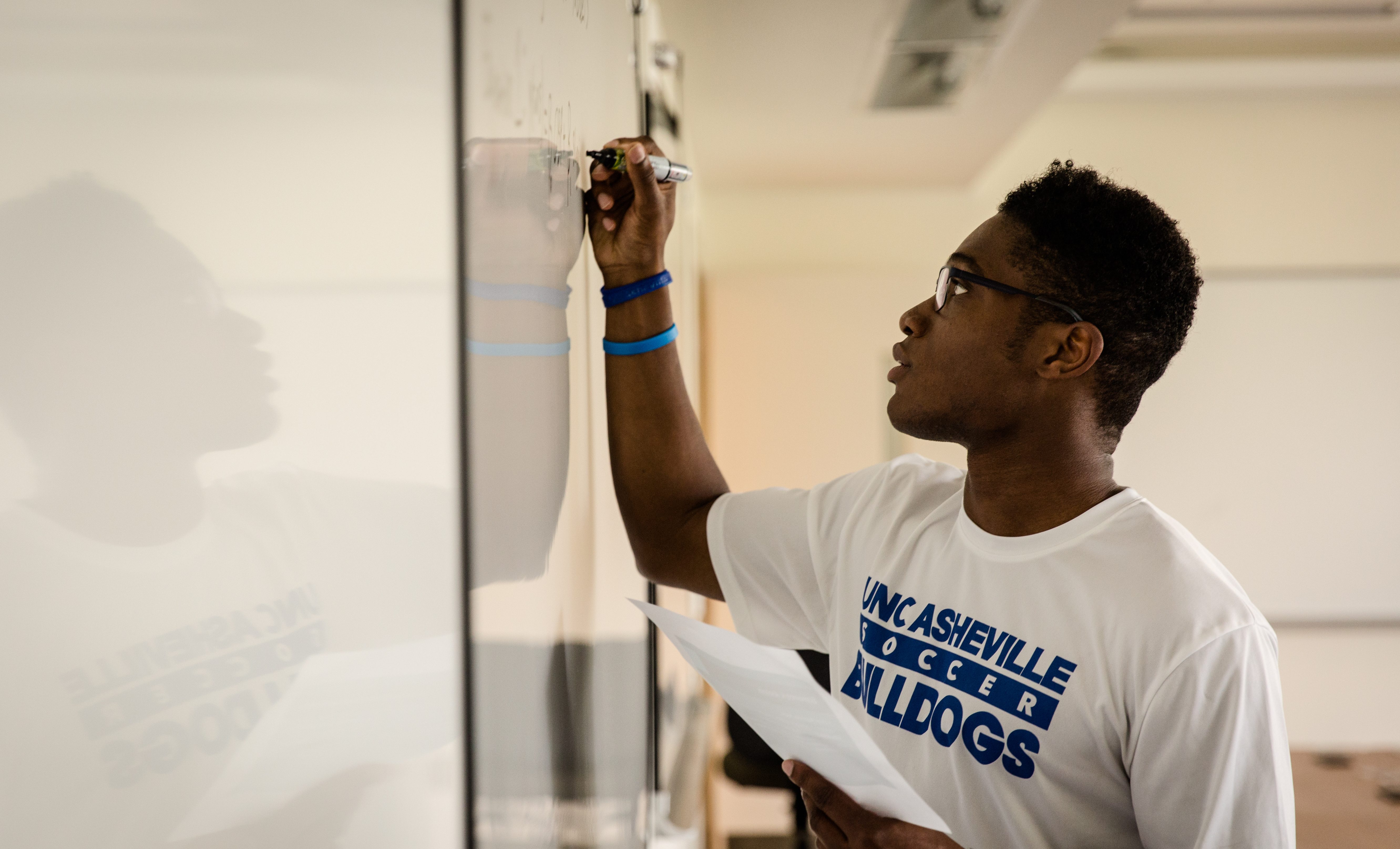 Economics student working on a problem at a white board