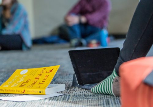 Why Buddhism is True book cover on the floor next to laptop