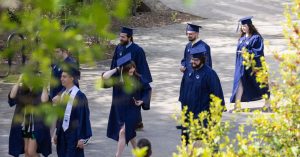 Students walking while wearing Commencement caps and gowns