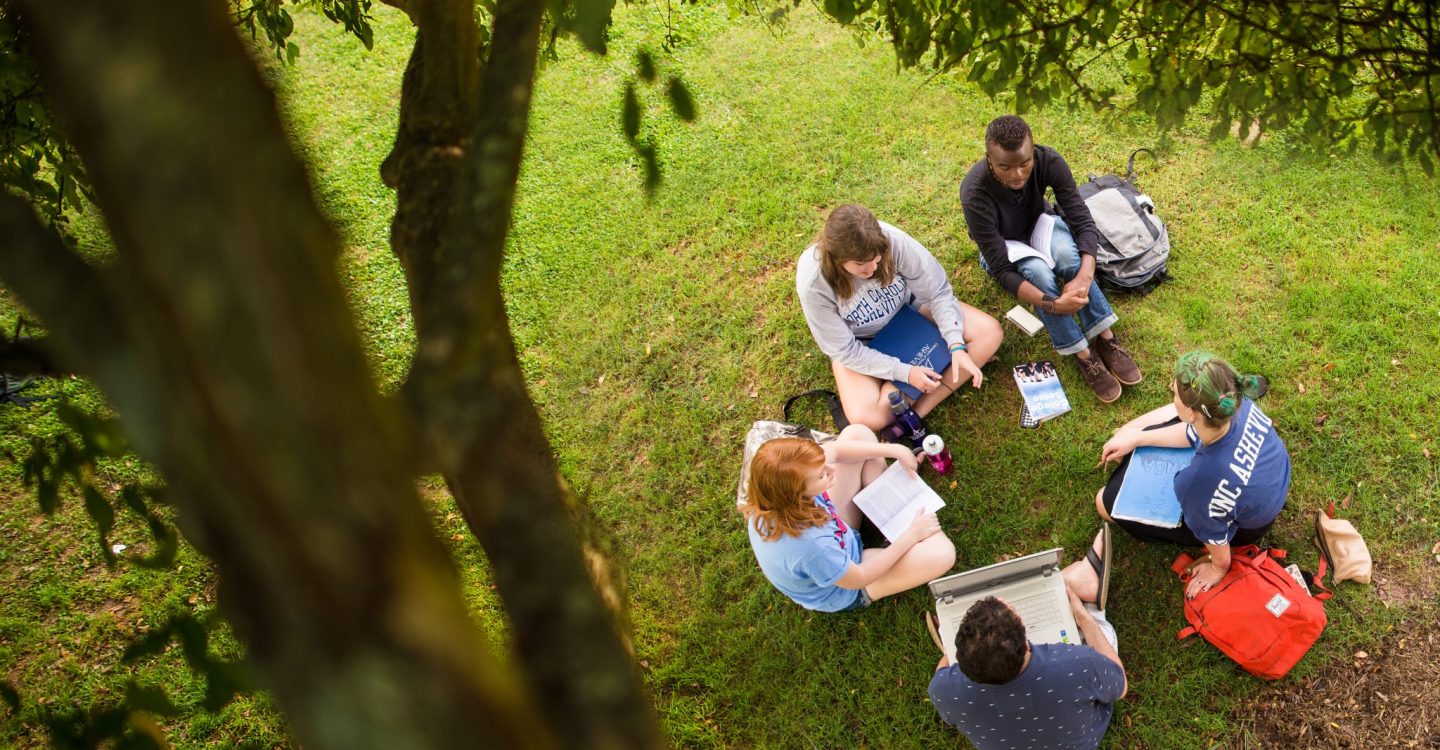 students sitting in a circle on the grass