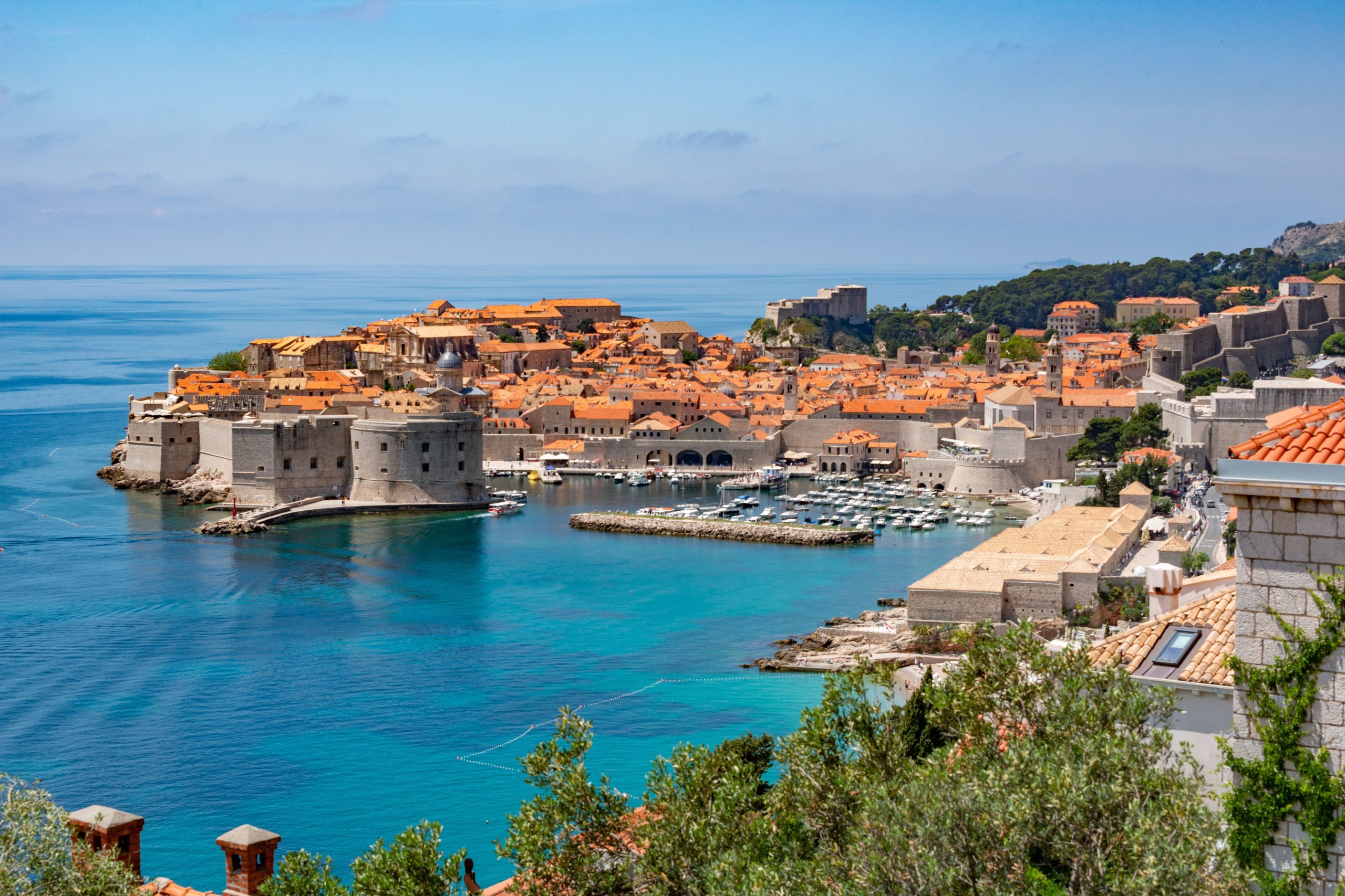 A vibrant, sun-drenched view of the Adriatic coastline in Croatia, featuring turquoise waters and historic architecture.